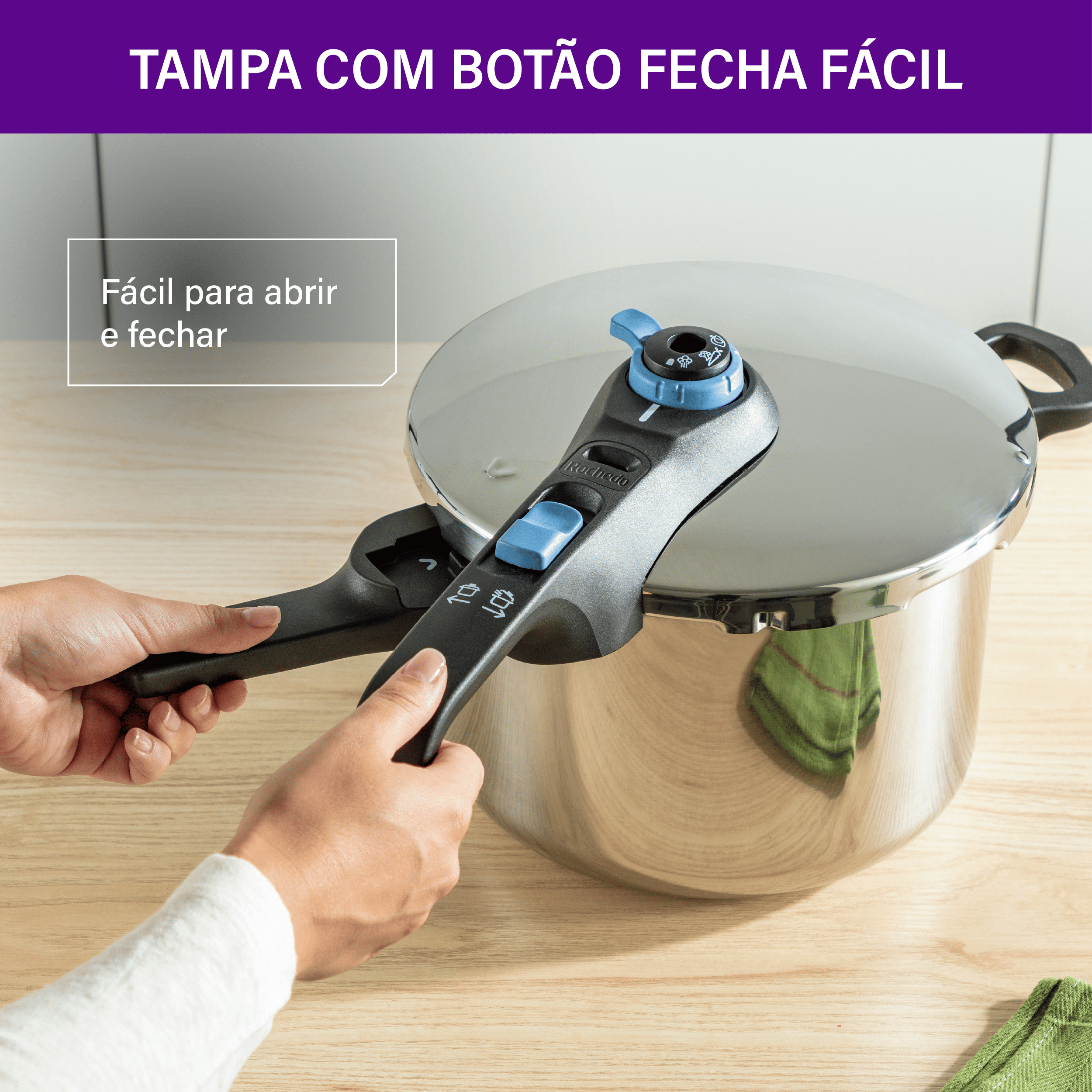 Detalhe das mãos operando o botão fecha fácil no cabo da panela de pressão Rochedo, demonstrando a praticidade no manuseio da tampa externa.