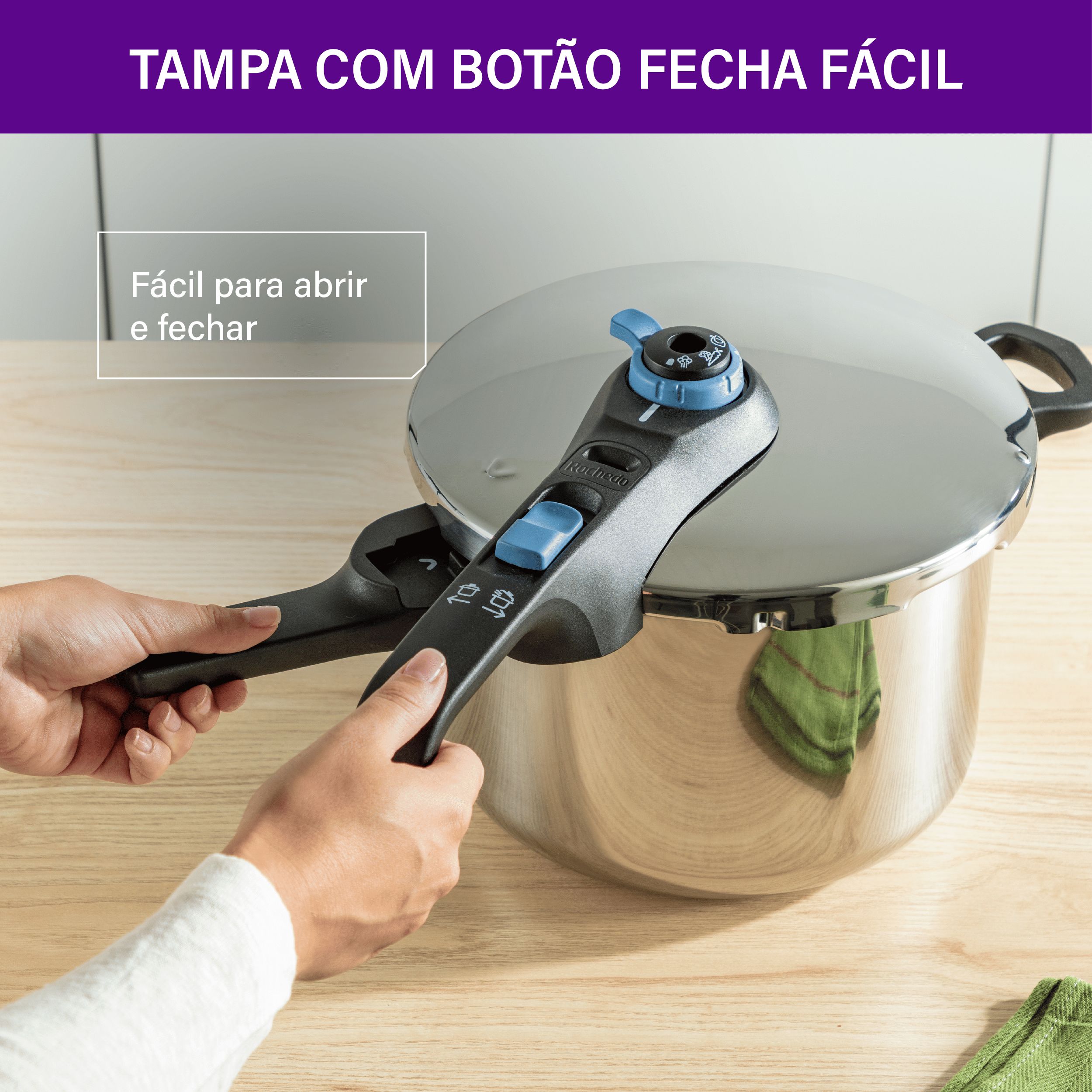 Mãos operando o sistema de fechamento externo da panela Rochedo. Texto "TAMPA COM BOTÃO FECHA FÁCIL" ressalta a praticidade.